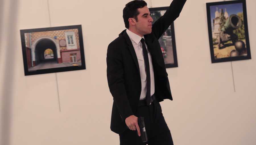 An unnamed gunman gestures after shooting the Russian Ambassador to Turkey, Andrei Karlov, at a photo gallery in Ankara, Turkey, Monday, Dec. 19, 2016.