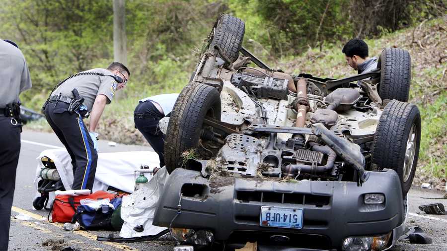 In this May 9, 2017 photo, medics pull a victim from an over turned vehicle in Woodbury, Conn. A second vehicle landed in a nearby stream. Katherine Ann Berman, wife of longtime ESPN broadcaster Chris Berman died in the traffic crash. (Steven Valenti/Republican-American via AP)