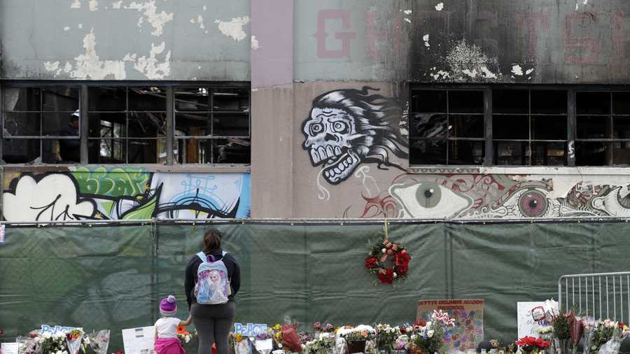 This Dec. 13, 2016 file photo shows flowers, pictures, signs and candles, are placed at the scene of a warehouse fire in Oakland, California.