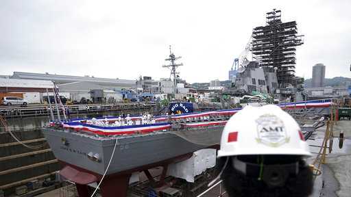 A worker looks at the USS John S. McCain at the U.S. Naval base in Yokosuka, southwest of Tokyo, Thursday, July 12, 2018. 