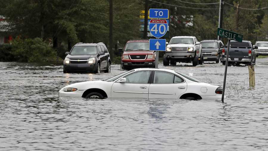 Cars try to navigate a flooded road leading to Interstate 40 in Castle Hayne, N.C., after damage from Hurricane Florence cut off access to Wilmington, N.C., Sunday, Sept. 16, 2018. (AP Photo/Chuck Burton)