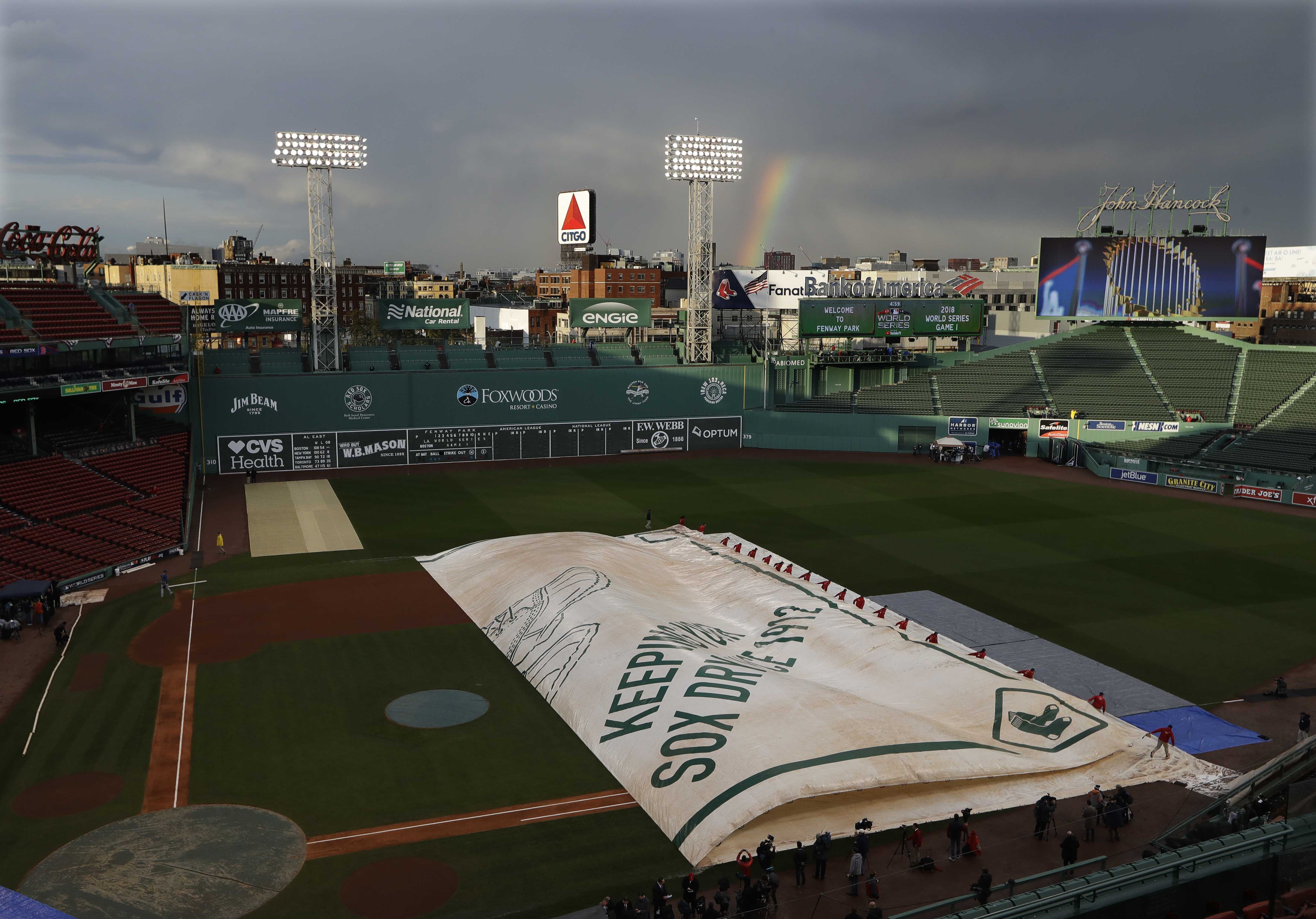 A rainbow adorned Boston Red Sox logo is displayed on the center field  video board as Colorado Rockies players warm up on Pride Night prior to a  baseball game at Fenway Park