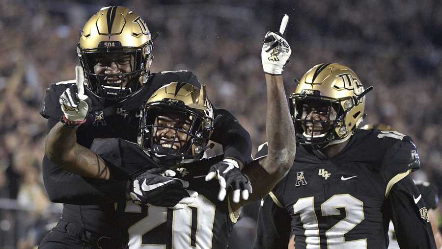 Central Florida defensive back Brandon Moore (20) is congratulated by linebacker Nate Evans, left, and linebacker Eric Mitchell after returning a blocked punt for 60 yards during the first half of an NCAA college football game against Cincinnati Saturday, Nov. 17, 2018, in Orlando, Fla. (AP Photo/Phelan M. Ebenhack)