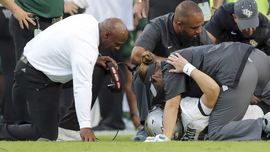 South Florida coach Charlie Strong, left, comforts Central Florida quarterback McKenzie Milton, who had injured his right leg during the first half of an NCAA college football game Friday, Nov. 23, 2018, in Tampa, Fla. (AP Photo/Mike Carlson)