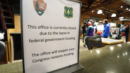 REI Co-op customers walk past an unstaffed ranger station kiosk, closed as part of the federal government shutdown, inside the flagship store Wednesday, Dec. 26, 2018, in Seattle. The desk is normally staffed by rangers who provide recreational information and passes for public lands in Washington state as part of a partnership with the National Park Service, US Forest Service, Washington State Parks, and REI. The shutdown started Saturday when funding lapsed for nine Cabinet-level departments and dozens of agencies.