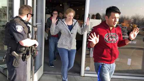 Shoppers with their hands raised are evacuated from Fashion Place Mall in Murray, Utah, after a shooting on Sunday, Jan. 13, 2019.