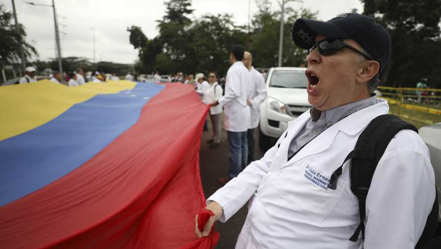 Venezuelan doctors shout slogans against the government of Venezuela's President Nicolas Maduro at the International Bridge Tienditas, which has been blocked by the Venezuelan military, near Cucuta, Colombia, Sunday, Feb. 10, 2019, across the border from Tachira, Venezuela. The doctors, who crossed into Colombia for the protest, are demanding their nation’s military allow humanitarian aid into the country, while Venezuelan President Nicolas Maduro contends the aid delivery is part of a larger U.S. intervention to remove him from power. (AP Photo/Fernando Vergara)