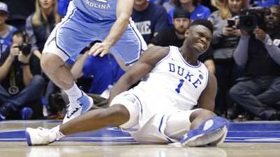 Duke's Zion Williamson (1) falls to the floor with an injury while chasing the ball with North Carolina's Luke Maye (32) during the first half of an NCAA college basketball game in Durham, N.C., Wednesday, Feb. 20, 2019.