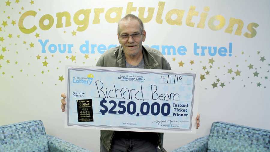 In this Monday, April 1, 2019 photo, made available by North Carolina Education Lottery, Richard Beare holds a large check after winning $250,000 in the North Carolina Education Lottery in Charlotte, N.C. Bears has stage 4 liver cancer and plans to use the money on a trip to Italy with his wife. (North Carolina Education Lottery via AP)