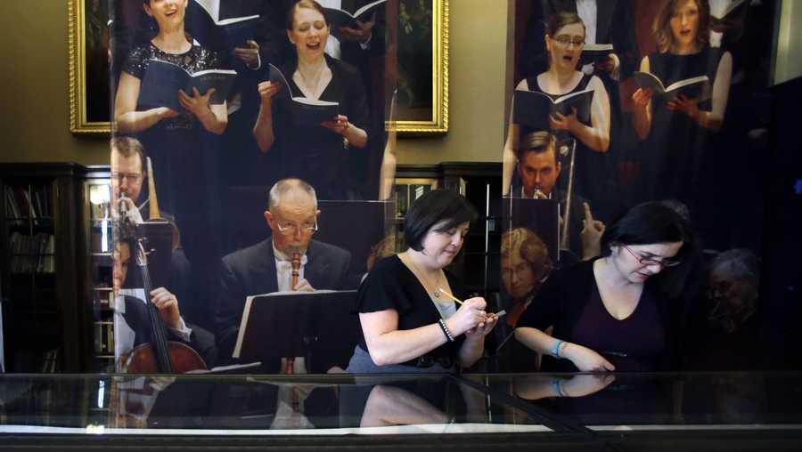 FILE - In this March 20, 2015. file photo, archivist Michelle Chiles, left, and exhibition developer Tamar Agulian help set up the Handel & Haydn Society bicentennial exhibit at the Boston Public Library in Boston. On Sunday, May 5, 2019, the Handel & Haydn Society was finishing a rendition of Mozart's "Masonic Funeral" at Boston's Symphony Hall when a youngster blurted out loudly: "WOW!" The organization has mounted a search for the kid it's calling the "Wow Child" — not to reprimand, but to offer a chance to meet the conductor. (AP Photo/Elise Amendola, File)