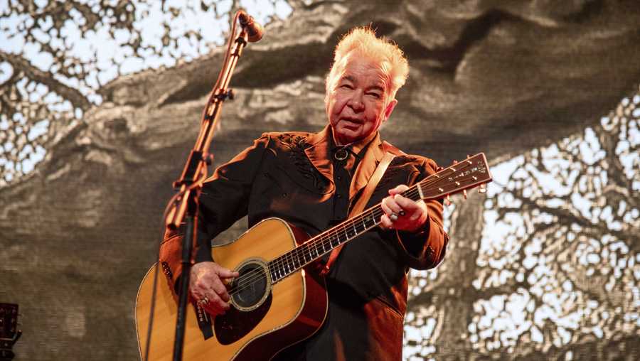 FILE - This June 15, 2019 file photo shows John Prine performing at the Bonnaroo Music and Arts Festival in Manchester, Tenn. Prine is postponing several shows this summer as he plans to have surgery to insert a stent to prevent a stroke. (Photo by Amy Harris/Invision/AP, File)