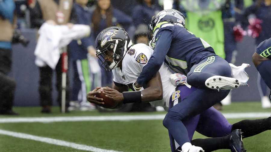 Baltimore Ravens quarterback Lamar Jackson (8) is hit by Seattle Seahawks cornerback Tre Flowers while scoring a touchdown on a fourth-down keeper play during the second half of an NFL football game, Sunday, Oct. 20, 2019, in Seattle. (AP Photo/Elaine Thompson)