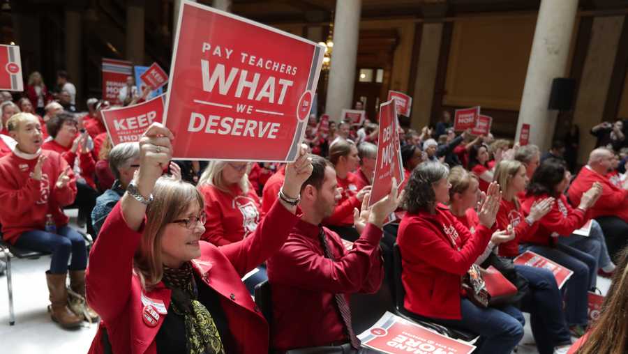 FILE - In this April 16, 2019 file photo, teachers cheer during a rally at at the Statehouse in Indianapolis. Indiana Gov. Eric Holcomb isn't promising any quick action on the call for further boosting teacher pay that thousands of educators will be making at the Statehouse next week. Teacher unions say at least 107 school districts with more than 40 percent of Indiana's students will be closed Tuesday, Nov. 19, 2019, while their teachers attend the rally. Holcomb didn't criticize school districts for closing, saying it was a local decision. (AP Photo/Michael Conroy, File)