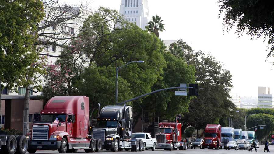 FILE - In this Nov. 13, 2009, file photo a caravan of trucks from the ports of Los Angeles and Long Beach, Calif., drive around Los Angeles City Hall during a protest against container fees being assessed against independent truckers. A federal judge on Thursday, Jan. 16, 2020, indefinitely blocked a new California labor law from applying to more than 70,000 independent truckers, ruling that it is preempted by federal rules on interstate commerce. (AP Photo/Damian Dovarganes, File)