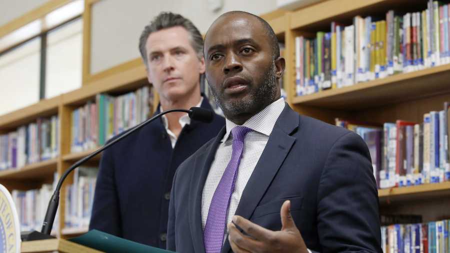 FILE — In this Oct. 31, 2019, file photo, state Superintendent of Public Instruction Tony Thurmond answers a reporter&apos;s question during a visit with California Gov. Gavin Newsom, background, to Blue Oak Elementary School in Cameron Park, Calif. Thurmond says that schools named for Confederate leaders or other racially charged figures exacerbate feelings of race and he commended schools that have opted to rename themselves. He said he applauds schools that have worked to rename themselves in more thoughtful and sensitive ways. Thurmond&apos;s comments, in response to a question at a media briefing, came after the Berkeley Unified School District board unanimously approved a plan last week to rename two schools named after founding fathers who were slaveholders. (AP Photo/Rich Pedroncelli, File)