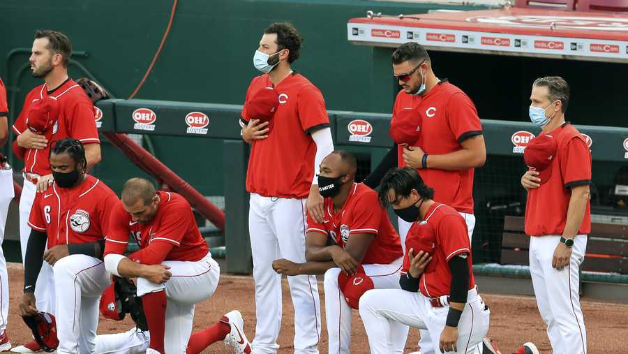 Cincinnati Reds&apos; Phillip Ervin, left, Joey Votto, left middle, Amir Garrett, middle, and Alex Blandino, right, kneel during the national anthem prior to an exhibition baseball game against the Detroit Tigers at Great American Ballpark in Cincinnati, Tuesday, July 21, 2020. (AP Photo/Aaron Doster)