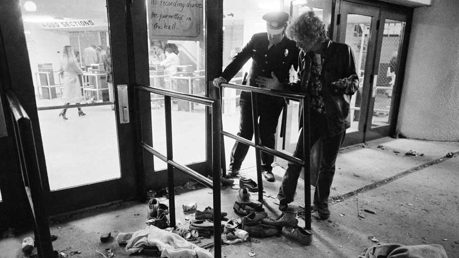A security guard and an unidentified man look at an area where several people were killed as they were caught in a surging crowd entering Cincinnati's Riverfront Coliseum for a Who concert on Monday. Shoes and clothes were strewn around the area where the people were killed and injured, shown Dec. 3, 1979. (AP Photo/Brian Horton)