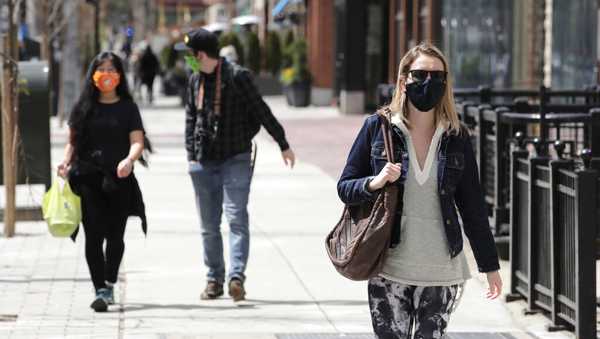 pedestrians, wearing masks due to the coronavirus outbreak, walk down boylston street in boston, wednesday, april 15, 2020.