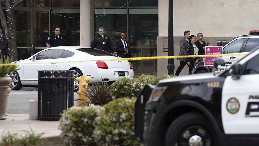 Investigators leave the Church of Scientology, at left rear, after a shooting in Inglewood, Calif., Wednesday, March 27, 2019. Two police officers and a suspect were shot Wednesday after law enforcement responded to reports of a man with a sword entering the Church of Scientology in Inglewood, authorities said. 