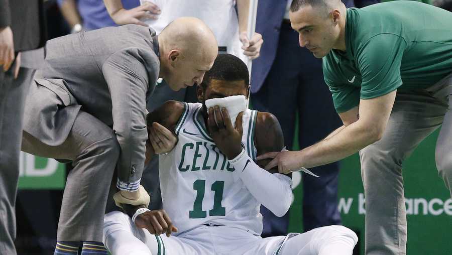 Team personnel assist Boston Celtics' Kyrie Irving (11) after he was injured during the first quarter of an NBA basketball game against the Charlotte Hornets in Boston, Friday, Nov. 10, 2017. Irving took an elbow to the face and left the game.