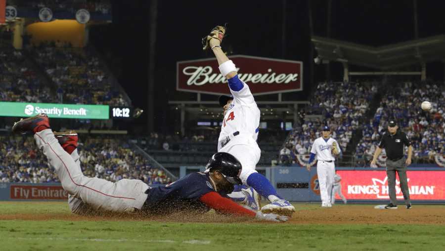 Boston Red Sox's Eduardo Nunez is safe at first past Los Angeles Dodgers first baseman Enrique Hernandez on a fielding error by relief pitcher Scott Alexander during the 13th inning in Game 3 of the World Series baseball game on Friday, Oct. 26, 2018, in Los Angeles. (AP Photo/David J. Phillip)