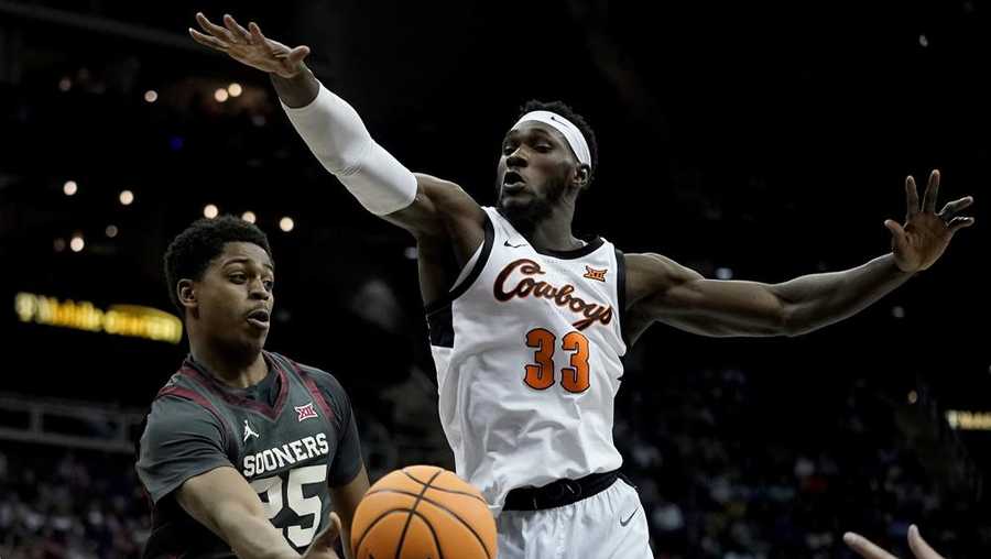 Oklahoma guard Grant Sherfield (25) passes around Oklahoma State forward Moussa Cisse (33) during the first half of an NCAA college basketball game in the first round of the Big 12 Conference tournament Wednesday, March 8, 2023, in Kansas City, Mo. (AP Photo/Charlie Riedel)