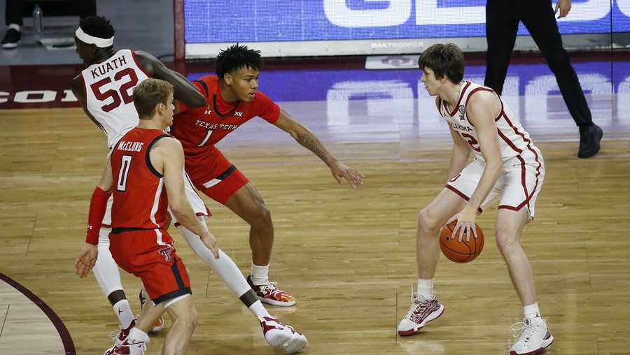 Oklahoma's Austin Reaves (12) watches as Kur Kuath (52) moves between Texas Tech's Mac McClung (0) and Terrence Shannon Jr. (1) during the first half of an NCAA college basketball game in Norman, Okla., Tuesday, Dec. 22, 2020. (AP Photo/Garett Fisbeck)