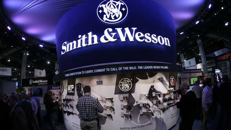 FILE - In this Tuesday, Jan. 14, 2014, file photo, trade show attendees examine handguns and rifles in the Smith & Wesson display booth at the Shooting Hunting and Outdoor Tradeshow, in Las Vegas.