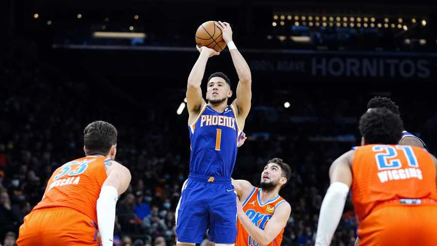 Phoenix Suns guard Devin Booker (1) shoots a 3-pointer over Oklahoma City Thunder guard Ty Jerome, middle, center Mike Muscala (33) and guard Aaron Wiggins (21) during the second half of an NBA basketball game Wednesday, Dec. 29, 2021, in Phoenix. The Suns won 115-97. (AP Photo/Ross D. Franklin)