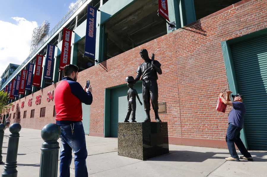 Pedestrians take photos of a statue of Boston Red Sox legend Ted Williams outside Fenway Park, Wednesday, Oct. 10, 2018, in Boston. Game 1 of the baseball American League Championship Series between the Red Sox and the Houston Astros is scheduled for Saturday in Boston. (AP Photo/Elise Amendola)
