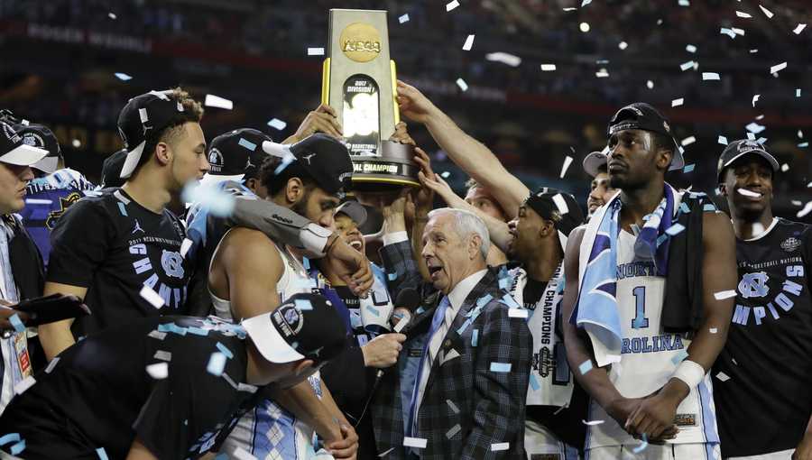 FILE - In this April 3, 2017, file photo, North Carolina head coach Roy Williams is interviewed as his team celebrate after the finals of the Final Four NCAA college basketball tournament against Gonzaga in Glendale, Ariz. North Carolina&apos;s national championship men&apos;s basketball team will not visit the White House because of a scheduling conflict. Team spokesman Steve Kirschner said Saturday, Sept. 23, 2017,  that Hall of Fame coach Roy Williams and the players were willing to go, and the university and White House tried "eight or nine" dates but none worked.
 (AP Photo/Mark Humphrey, File)