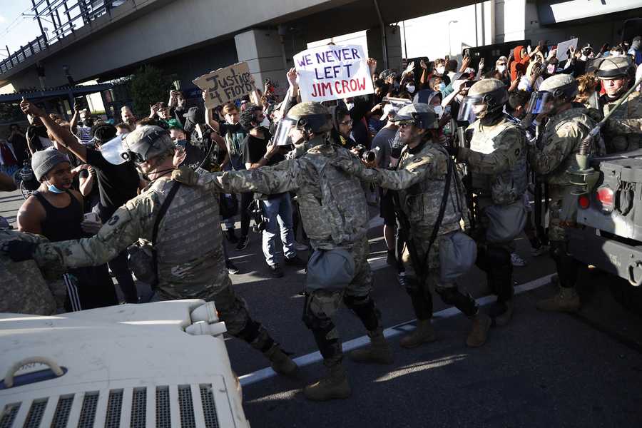 Minnesota National Guard walk past protesters Friday, May 29, 2020, in Minneapolis. Protests continued following the death of George Floyd, who died after being restrained by Minneapolis police officers on Memorial Day. (AP Photo/John Minchillo)