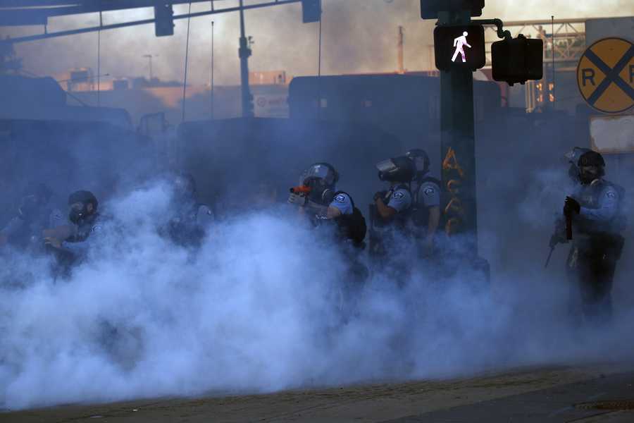 A police officer prepares to shoot tear gas Friday in Minneapolis. Protests continued following the death of George Floyd who died after being restrained by Minneapolis police officers on Memorial Day.