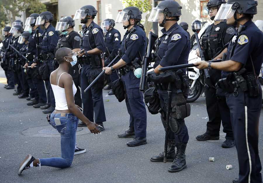 A masked protestor kneels before San Jose police on Friday, May 29, 2020, in San Jose, Calif. (AP Photo/Ben Margot)