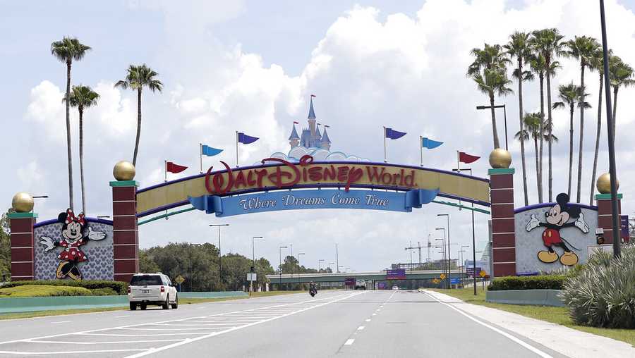 Cars drive under a sign greeting visitors near the entrance to Walt Disney World, Thursday, July 2, 2020, in Lake Buena Vista, Fla.