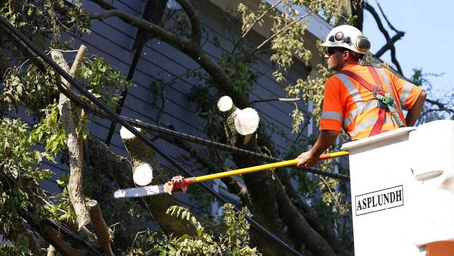 A worker trims a tree brunch around power line, Friday, Aug. 14, 2020, in Cedar Rapids, Iowa. The storm that struck Monday morning left tens of thousands of Iowans without power as of Friday morning. (AP Photo/Charlie Neibergall)
