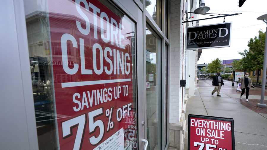 FILE - In this Wednesday, Sept. 2, 2020, file photo, passers-by walk past a business storefront with store closing and sale signs in Dedham, Mass. The Labor Department said Tuesday, Oct. 6, 2020,  that the number of U.S. job postings on the last day of August dipped to 6.49 million, down from 6.70 million July. (AP Photo/Steven Senne, File)