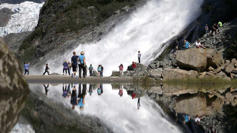In this July 31, 2013, file photo, tourists visiting the Mendenhall Glacier in the Tongass National Forest are reflected in a pool of water as they make their way to Nugget Falls in Juneau, Alaska.