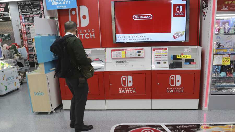 A shopper looks at Switch from Nintendo at an electronics store in Tokyo, Monday, Nov. 2, 2020. Nintendo, the Japanese company behind Super Mario and Pokemon video games, reported Thursday that its fiscal first half profit more than tripled as passed time while stuck at home during the pandemic playing games. (AP Photo/Koji Sasahara)