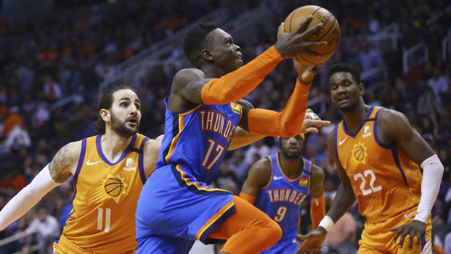 Oklahoma City Thunder guard Dennis Schroder (17) drives past Phoenix Suns guard Ricky Rubio (11) as Suns center Deandre Ayton (22) and Thunder center Nerlens Noel (9) watch during the first half of an NBA basketball game in Phoenix, in this Friday, Jan. 31, 2020, file photo.