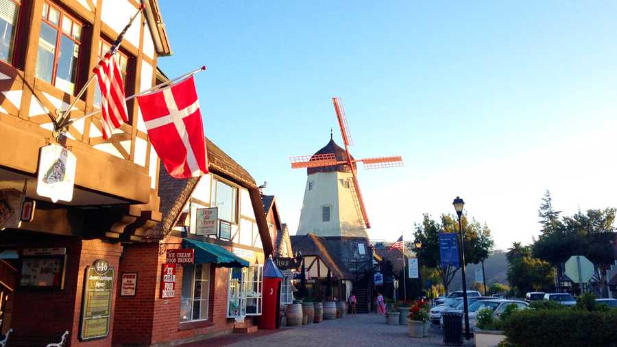 FILE - This Sept. 30, 2014 photo shows the Danish flag flying on Alisal Road in Solvang, Calif., on Sept. 30, 2014.  Founded in 1911 by Danish immigrants, Solvang is a touristy enclave with Danish bakeries, Danish-themed hotels and even a Hans Christian Andersen Museum. The location is featured in a collection of mini-essays by American writers published online by the Frommer&apos;s guidebook company about places they believe helped shape and define America.  (AP Photo/Solvej Schou, File)