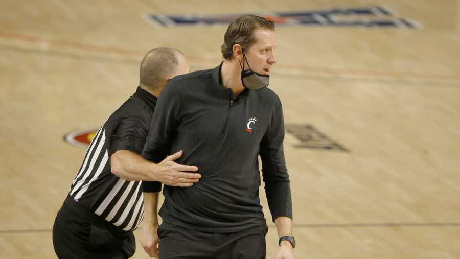 Cincinnati head coach John Brannen is pulled back toward the team bench by a game official as Cincinnati plays Wichita State during the second half of an NCAA college basketball game in the semifinal round of the American Athletic Conference men's tournament Saturday, March 13, 2021, in Fort Worth, Texas. (AP Photo/Ron Jenkins)