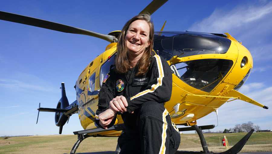 Air ambulance flight paramedic, Rita Krenz, poses in front of her company's helicopter in Weyers Cave, Va., Monday, March 15, 2021. (AP Photo/Steve Helber)