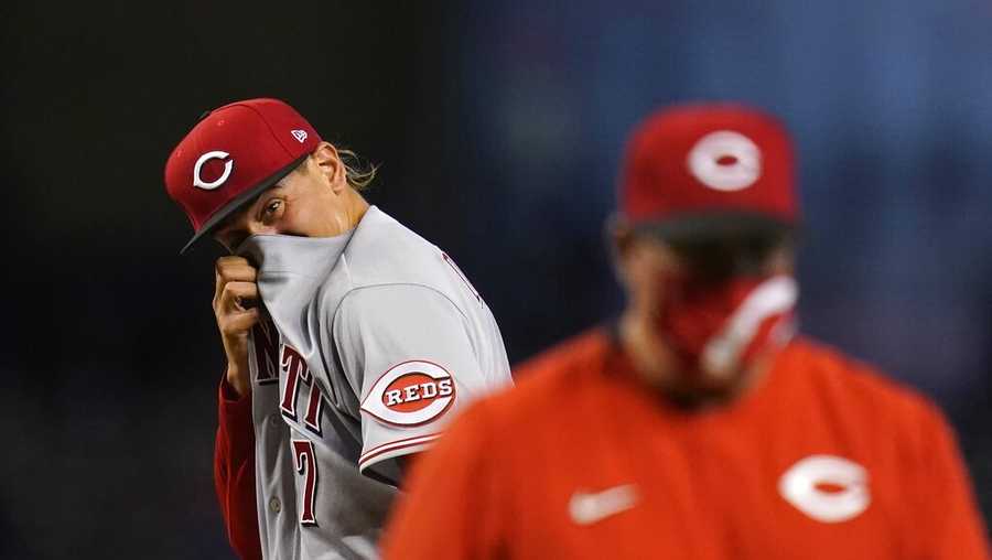 Cincinnati Reds starting pitcher Jose De Leon, left, wipes sweat from his face after getting a visit from Reds pitching coach Derek Johnson, right, as a result of giving up a three-run home run to Arizona Diamondbacks&apos; David Peralta and during the third inning of a baseball game Sunday, April 11, 2021, in Phoenix. (AP Photo/Ross D. Franklin)