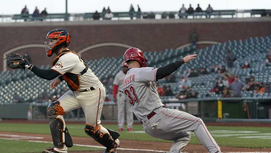 Cincinnati Reds&apos; Jesse Winker (33) slides home to score past San Francisco Giants catcher Buster Posey during the second inning of a baseball game in San Francisco, Tuesday, April 13, 2021. (AP Photo/Jeff Chiu)