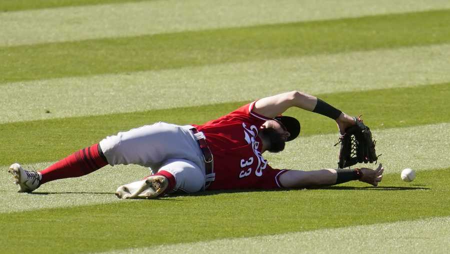 Cincinnati Reds left fielder Jesse Winker dives but misses on a fly ball from Los Angeles Dodgers' Matt Beaty during the eighth inning of a baseball game Wednesday, April 28, 2021, in Los Angeles. Beaty got an RBI single on the play. (AP Photo/Marcio Jose Sanchez)