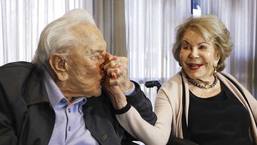 FILE - In this May 4, 2017, file photo, Kirk Douglas kisses his wife Anne's hand, in Los Angeles during a party celebrating his 100th birthday. (AP Photo/Reed Saxon, File)