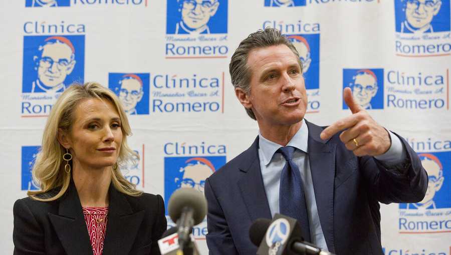 FILE - In this March 28, 2019, file photo, California Gov. Gavin Newsom with his wife, Jennifer Siebel Newsom attend a roundtable discussion with Central American community leaders at the Clinica Monsenor Oscar Romero in Los Angeles. Gov. Newsom said he "absolutely" sees no conflict of interest with a nonprofit launched by his wife accepting donations from companies that lobby his administration. He was responding to a reporter in The Sacramento Bee that found The Representation Project, the nonprofit launched by Jennifer Siebel Newsom, received at least $800,000 from corporations that lobby state government. (AP Photo/Damian Dovarganes, File)