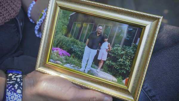 Noreen Wasti shows a framed family photo of herself as a child with her father, Thursday June 24, 2021, in Brooklyn, N.Y. Wasti lost her father Salman Wasti, 76, a retired biology professor from Glocester, R.I., the day after Christmas last year to COVID-19 and is having a hard time coping with his death.