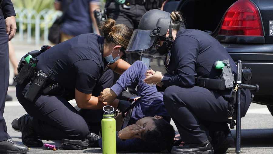 Los Angeles Police officer Gutierrez, left, puts pressure on the open wound of a demonstrator, who was stabbed during clashes between anti-vaccination demonstrators and counter-protesters during an anti-vaccination protest in front of the City Hall in Los Angeles on Saturday, Aug. 14, 2021. A man was stabbed and a reporter was attacked Saturday at a protest against vaccine mandates on the south lawn of Los Angeles&apos; City Hall after a fight broke out between the protesters and counter-protesters, the Los Angeles Police Department and local media said. (AP Photo/Damian Dovarganes)